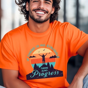 May include: Bright orange t-shirt with the text "IF THERE IS NO STRUGGLE, THERE IS NO PROGRESS" in a retro design. The graphic features a silhouette of a person with arms raised, a mountain, trees, and a sunset.