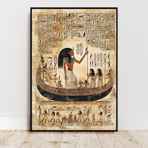 May include: Framed print of an ancient Egyptian scene. The artwork shows a woman in a boat, surrounded by figures and hieroglyphs. The colour palette includes browns, blacks, and golds, creating a historical and artistic aesthetic. The print is framed in a black border.