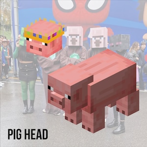 Pode incluir: Uma cabeça de porco rosa pixelizada com uma coroa dourada e colorida é erguida em frente a uma multidão. Um porco rosa pixelizado maior está em frente à multidão. O texto "PIG HEAD" está na parte inferior.