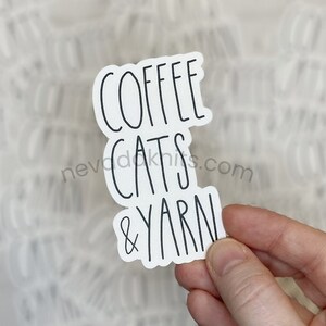 May include: White sticker with black text that reads "Coffee Cats & Yarn".