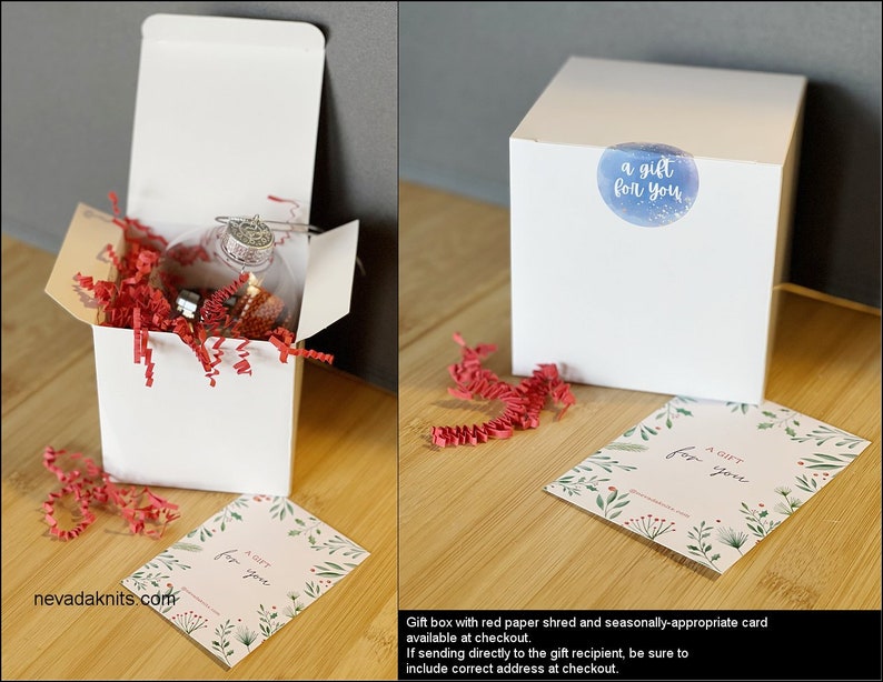 May include: A white gift box filled with red tissue paper and a clear glass ornament. The box has a sticker that says "a gift for you". A separate card with the same text is included.