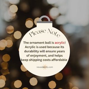 May include: A white Christmas ornament with the text "Please Note" and the message "The ornament ball is acrylic! Acrylic is used because its durability will ensure years of enjoyment, and helps keep shipping costs affordable." The ornament also includes the website "nevadaknits.com".