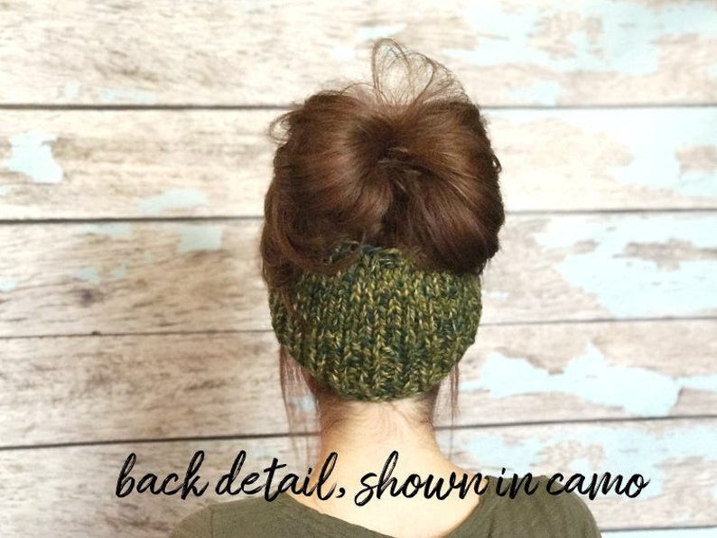 May include: Back view of a green and brown knit headband worn by a person with brown hair in a bun. The headband is made of a soft, stretchy knit fabric.