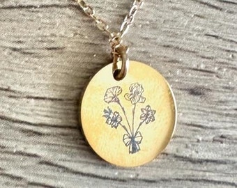 May include: A gold necklace with a round pendant featuring a black and white engraved floral design.