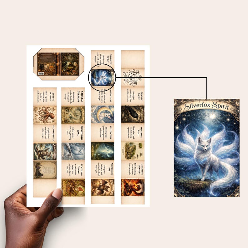 Op de afbeelding: Een hand houdt een vel papier met illustraties en tekst vast. Het vel bevat een kaart met een witte vos met negen staarten, getiteld "Silverfox Spirit". Andere kaarten tonen verschillende wezens en tekst.