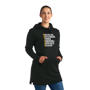 May include: Black hooded sweatshirt with a long length. The front of the sweatshirt has the word "MOTHER" spelled vertically in yellow with the letters "M", "O", "T", "H", "E", and "R" each representing a word: "Marvelous", "Outstanding", "Tender", "Honorable", "Empathetic", and "Resilient".