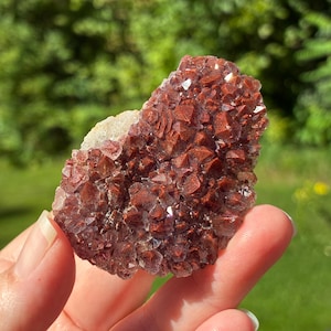 May include: A cluster of deep red, iron-stained quartz crystals with a jagged, crystalline surface texture. The mineral specimen features numerous small, pointed points that catch the light, displaying a rich, earthy crimson hue throughout.