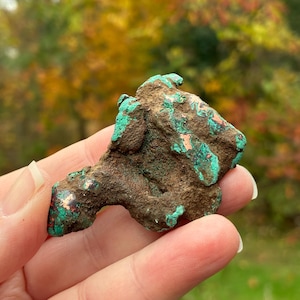 May include: A raw, irregular mineral specimen featuring a textured, earthy brown surface with vibrant patches of bright turquoise and copper-coloured mineral deposits. The piece has a jagged, organic shape with visible crevices and rough edges.