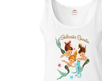 May include: White tank top with a graphic of three mermaids and a seahorse. The text "Saltwater Sweetie" is printed in gold above the mermaids.