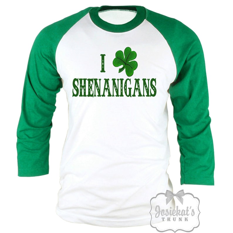 May include: White and green raglan-style shirt with the text "I &hearts; SHENANIGANS" and a green shamrock. The sleeves are green, and the body is white. The shirt has a round neckline.