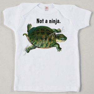 May include: White baby onesie with a green turtle illustration and the text "Not a ninja."