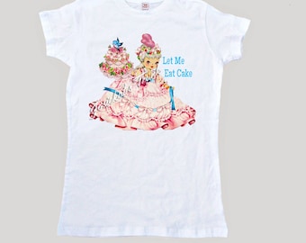 May include: White t-shirt with a vintage illustration of a girl in a pink dress holding a cake. The text "Let Me Eat Cake" is printed in blue on the shirt.