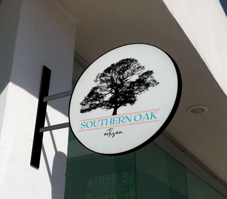 May include: A circular, wall-mounted sign featuring a black silhouette of an oak tree. Below the tree, the text reads SOUTHERN OAK in blue capital letters, flanked by two horizontal lines, with the word artisan in black script underneath.