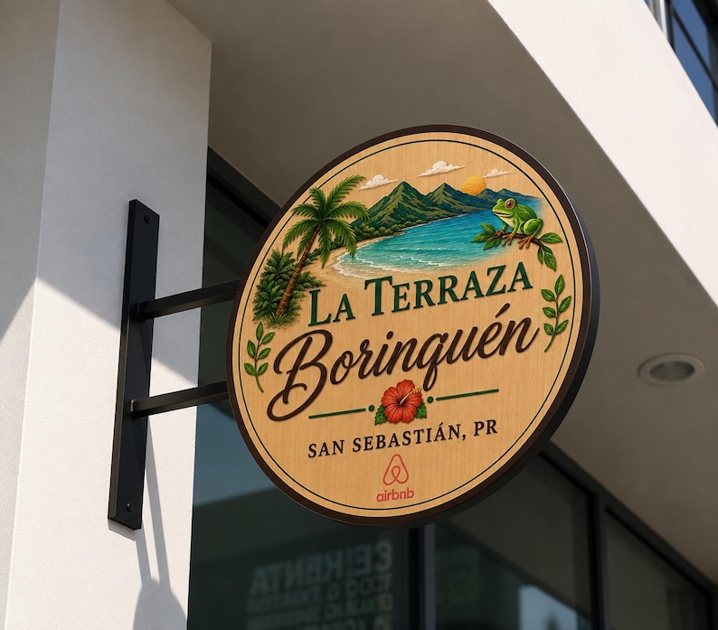 May include: A circular wooden sign mounted on a black metal bracket featuring a painted tropical landscape with a beach, mountains, a palm tree, and a green frog. The text reads La Terraza Borinqu&eacute;n, San Sebasti&aacute;n, PR, with an Airbnb logo below.