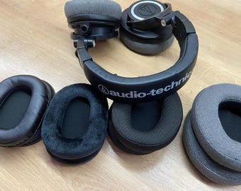 May include: A set of five ear pads for headphones. The ear pads are made of different materials, including leather, fabric, and velour. The ear pads are in various colors, including black, gray, and brown. The ear pads are designed to fit over the ears and provide a comfortable listening experience.
