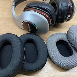 May include: Four replacement ear pads for headphones. Two are black with a textured surface and two are gray with a textured surface.