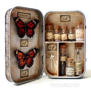 May include: A vintage tin box with a hinged lid, decorated with butterflies and musical notes. The inside of the box contains small glass vials with cork stoppers, labeled with numbers and the word "Specimen".