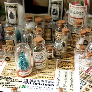Puede incluir: Una colección de pequeñas botellas de vidrio con tapones de corcho y etiquetas. Las botellas están llenas de varios artículos, incluyendo nieve, pequeños árboles y otros elementos decorativos. Las etiquetas en las botellas presentan temas festivos navideños y texto, como "Magia Navideña" y "Una Feliz Navidad".