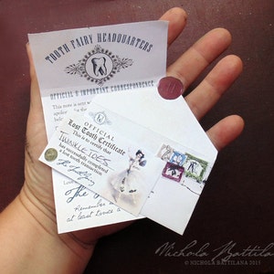 Puede incluir: Un sobre blanco con un sello de cera roja y una nota manuscrita que dice "OFFICIAL Lost Tooth Certificate This is to certify that TWINKLE TOES has successfully completed a lost tooth transaction The Tooth Fairy Love The Fairy Remember to brush at least twice a day"