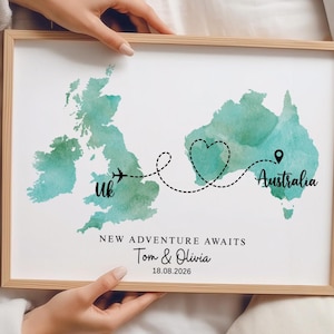 May include: A framed print featuring watercolour maps of the UK and Australia in teal. A dashed line with an aeroplane icon connects the two, forming a heart shape. Text includes "UK", "Australia", "NEW ADVENTURE AWAITS", "Tom & Olivia", and "18.08.2026".