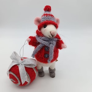 Peut inclure: Figurine de souris blanche en feutre, vêtue d'un manteau rouge, d'une écharpe et d'un bonnet gris, tenant une décoration rouge avec un nœud gris. La souris a des oreilles roses et des bottes grises. L'ornement mesure environ 5 cm de diamètre.