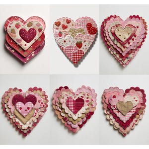 Peut inclure: Six décorations en tissu en forme de cœur, dans des tons de rose, de rouge et de beige. Chaque cœur présente des motifs superposés avec des motifs de fraises, de pois et de carreaux. Les cœurs sont disposés sur un fond blanc.