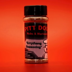 Puede incluir: Un tarro de vidrio de mezcla de especias marrón con una tapa negra y una etiqueta blanca que dice "PITT DOG Rubs & Marinade" y "Errythang Seasoning" con un perro de dibujos animados con un gorro de chef.
