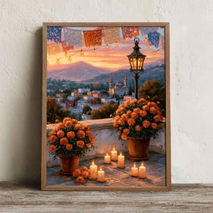 Puede incluir: Una impresión artística enmarcada que muestra una vista al atardecer de un pueblo con una iglesia, dos macetas de terracota con flores de cempasúchil naranjas, un farol de metal negro y varias velas encendidas en una terraza de piedra.