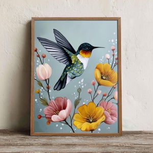 May include: A framed wall art print featuring a hummingbird with iridescent green and black feathers, a bright orange throat, and a white chest, hovering amidst a collection of yellow and pink flowers against a soft light blue background.