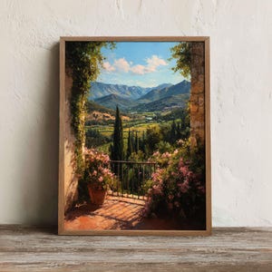 May include: A framed landscape painting depicts a Tuscan vista. The artwork showcases a balcony with potted flowers, a wrought-iron railing, and a view of rolling hills, cypress trees, and a blue sky with clouds. The frame is made of wood.