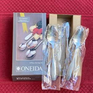May include: A new 4-piece serving set by Oneida, still in its original packaging. The set includes spoons and knives, with a box that reads "18/8 Stainless Made in U.S.A. Full Lifetime Warranty."