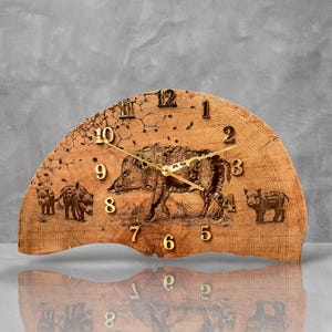 May include: A wooden clock with a wild boar design. The clock face is made of wood and has gold-colored numbers and hands. The clock is shaped like a half-circle and has a rustic look.