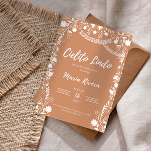Könnte beinhalten: Pfirsichfarbene Babyparty-Einladung mit weißen Blumen- und Blättermotiven. Der Text "Cielito Lindo" ist in Weiß geschrieben. Details sind der Name Maria Rivera, das Datum 16. August 2025 und die Uhrzeit 12:00 Uhr.