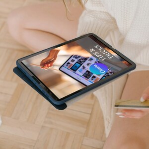 May include: A dark blue tablet with a screen displaying the Canva logo and the words "TIPS & TRICKS". The tablet is in a dark blue case. The screen shows a variety of images and a hand holding a stylus.