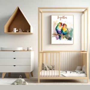 Puede incluir: Una pintura de acuarela de dos coloridos pájaros del amor posados en una rama, con la palabra "Juntos" escrita encima. La pintura está enmarcada y colgada en una pared de una guardería.