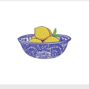 May include: An embroidery design featuring a blue and white bowl with a detailed floral pattern filled with three yellow lemons and two small green leaves. The stitching creates a textured appearance for the fruit and the decorative bowl.
