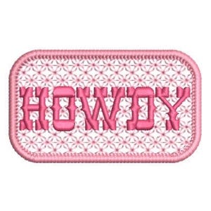 May include: A rectangular embroidered patch with rounded corners featuring the word HOWDY in pink block lettering. The background consists of a repeating pink floral or star-like pattern, and the entire edge is finished with a thick pink stitched border.