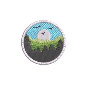 May include: A circular embroidered patch featuring a landscape scene with a light blue sky, a pale gray moon, and three small black birds in flight. Below the sky, a layer of green hills sits above a dark gray forest of pine trees.