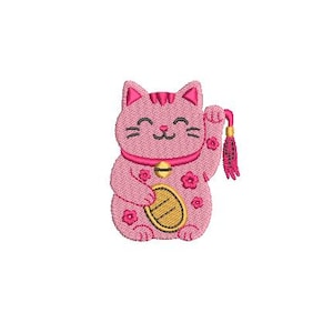 May include: Embroidered pink Maneki Neko cat with a raised paw, a gold coin, and a bell collar. The cat has a smiling face and is decorated with flower details. A tassel hangs from the raised paw.