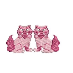May include: An embroidery design featuring two symmetrical guardian lion figures in shades of light and dark pink. Each lion is depicted in a seated position with stylized manes, sharp teeth, and curled tails, rendered with detailed thread stitching.