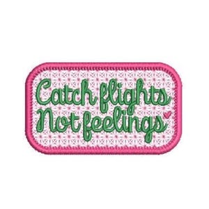 May include: A rectangular embroidered patch with rounded corners, featuring a pink border and a white background with a pink cross-stitch pattern. The text Catch flights Not feelings is stitched in green cursive, with a small pink heart icon.