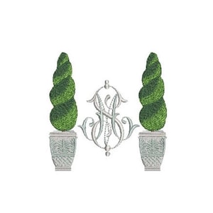 May include: An embroidery design featuring two green spiral topiary trees in light gray planters, flanking a central silver-toned monogram with the letters SH intertwined in a decorative, ornate script style against a plain white background.