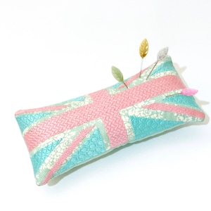 Peut inclure: Un coussin &agrave; &eacute;pingles bleu clair et rose avec un motif Union Jack. Le coussin &agrave; &eacute;pingles a plusieurs &eacute;pingles avec des t&ecirc;tes d&eacute;coratives qui en sortent.