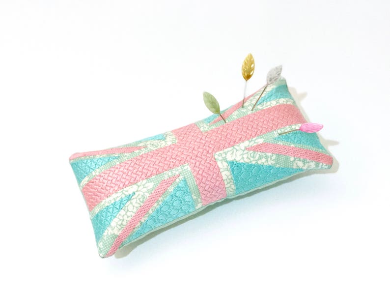 Peut inclure: Un coussin &agrave; &eacute;pingles bleu clair et rose avec un motif Union Jack. Le coussin &agrave; &eacute;pingles a plusieurs &eacute;pingles avec des t&ecirc;tes d&eacute;coratives qui en sortent.