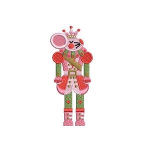 May include: An embroidered patch featuring a mouse dressed as a nutcracker soldier. The mouse wears a pink crown, a pink and red uniform with gold accents, and green trousers. The design uses pink, red, green, and gold thread on a white background.