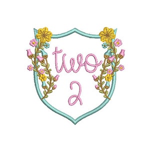 Peut inclure: Un bouclier bleu clair avec une bordure florale et le texte "two 2" en rose.