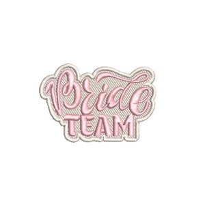 Puede incluir: Parche bordado en rosa y blanco con el texto "Bride Team" en una fuente cursiva.