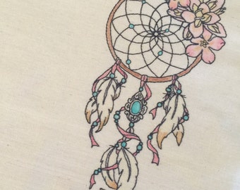 May include: A brown dreamcatcher with a turquoise stone and feathers hanging from it. The dreamcatcher is decorated with pink flowers.