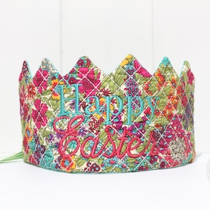 May include: A colourful fabric crown with a quilted design and the words "Happy Easter" embroidered in turquoise and red.