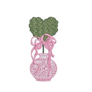 Op de afbeelding: Een geborduurd ontwerp met een lichtroze vaas met ingewikkelde reliëfpatronen, met daarin een groene hartvormige topiary. Een decoratief lichtroze lint is rond de steel van de topiary gestrikt, met lange, vloeiende lussen en uiteinden.